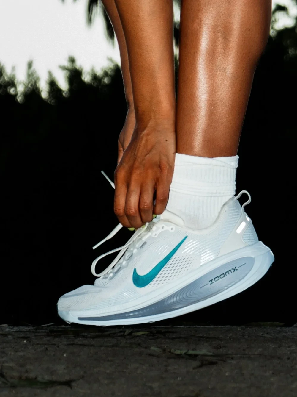 White Nike running shoe being laced outdoors